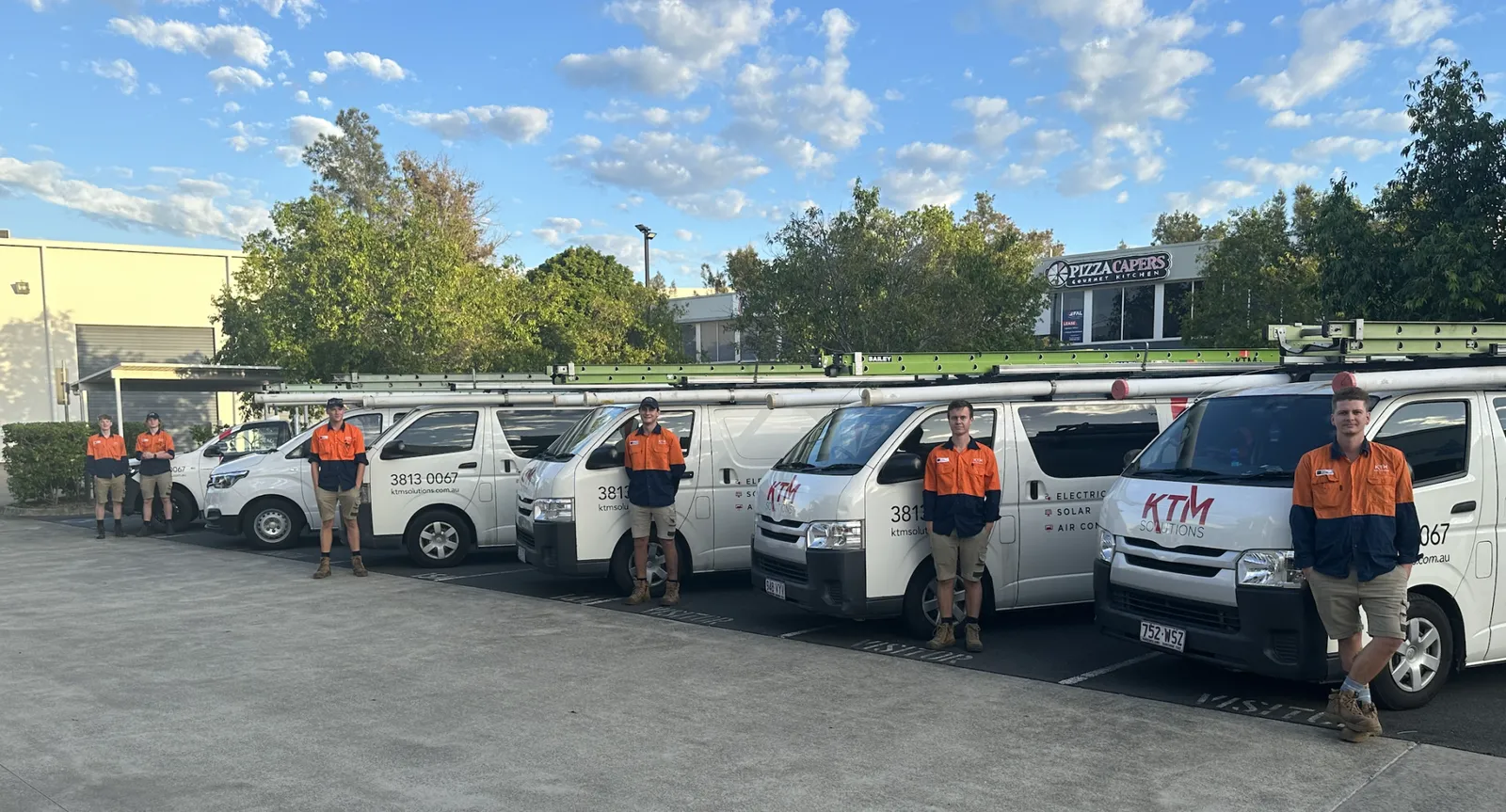 The full KTM Solutions team standing with the service fleet