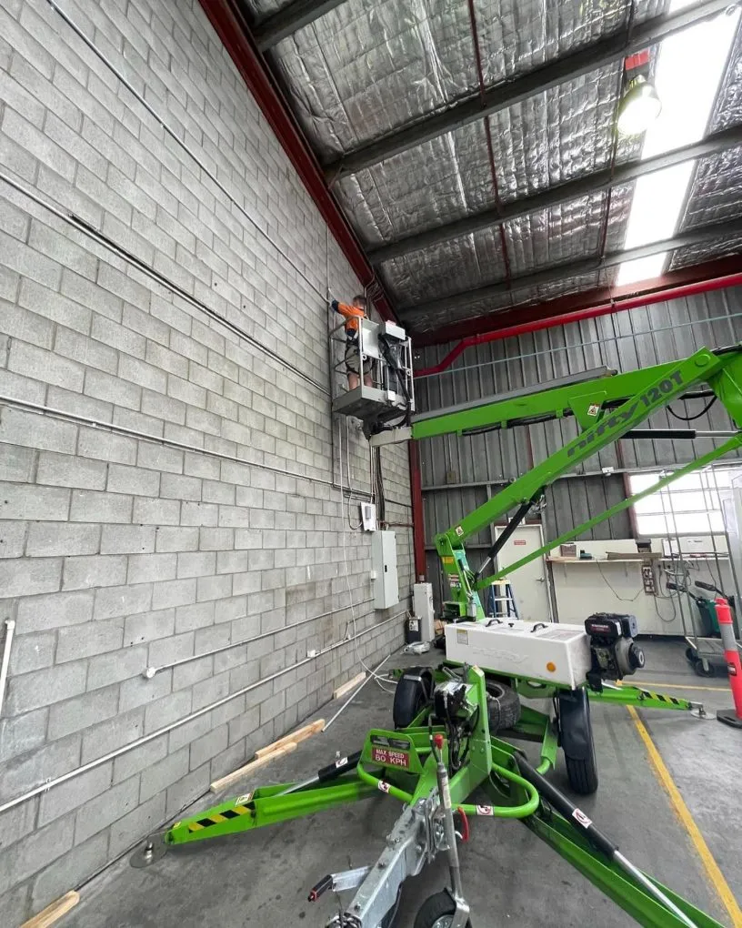 A KTM electrician working at height in a warehouse from an elevated work platform